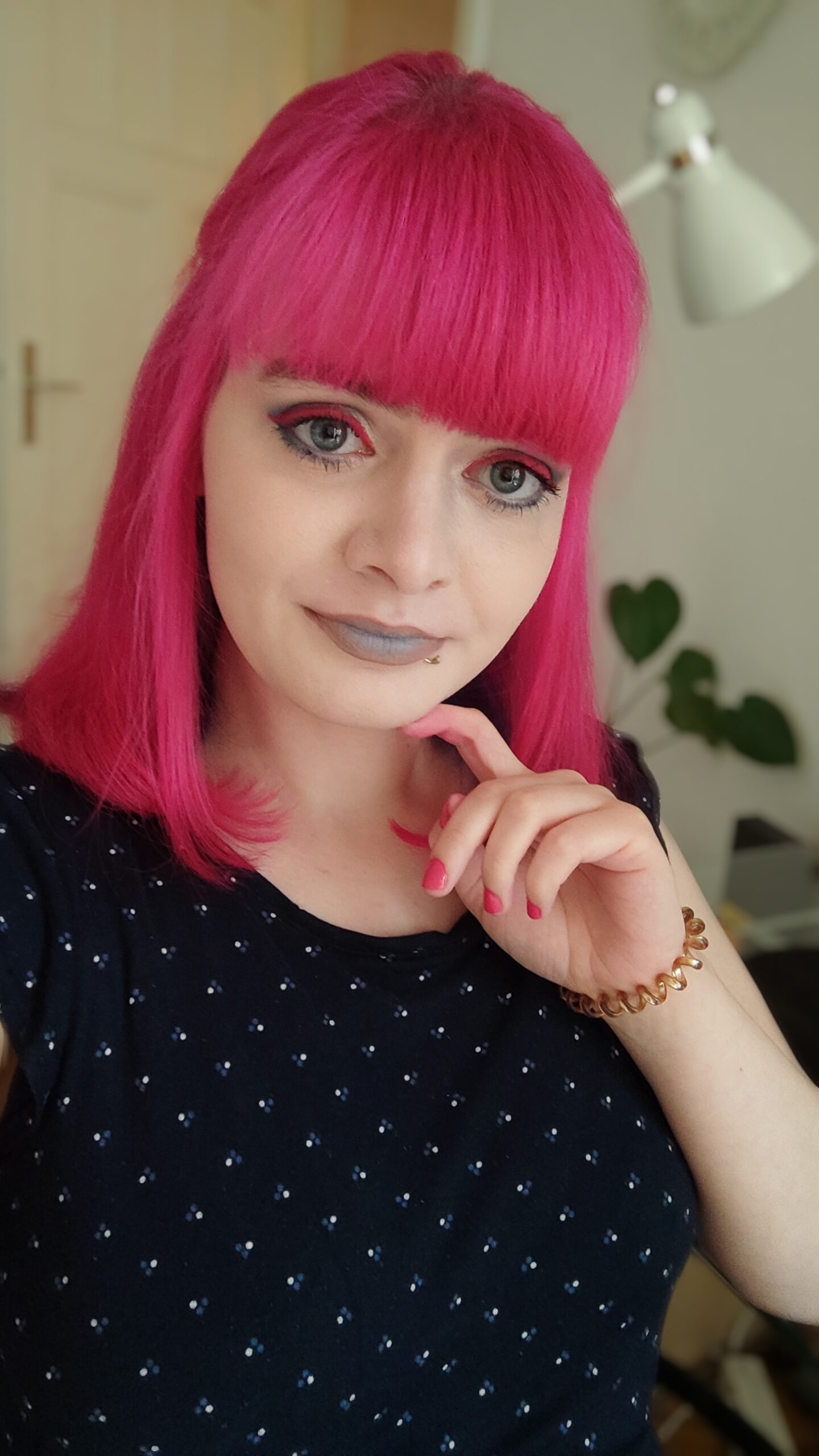 Lucia schaut in die Kamera, sie trägt Make-up in ihren neuen Brandingfarben: Pinkfarbenen Lidstrich, beigen Lidschatten und beige-blauen Lippenstift. Außerdem pink lackierte Fingernägel und ein dunkelblaues T-Shirt.